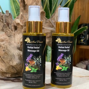 A bottles of Herbal Relief Massage Oil with gold spray dispensers, placed against a rustic wooden backdrop. The dark labels feature botanical illustrations, highlighting key ingredients like jojoba, calendula, eucalyptus, and ginger oils for muscle relaxation and skin nourishment